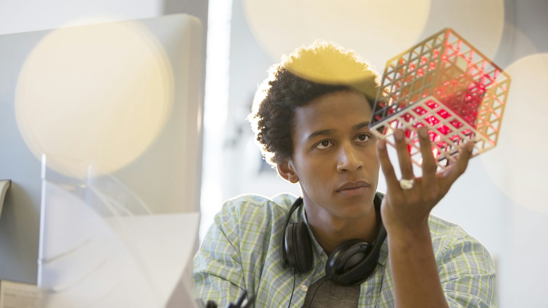 An engineering student looks at a 3D-printed model of a square.